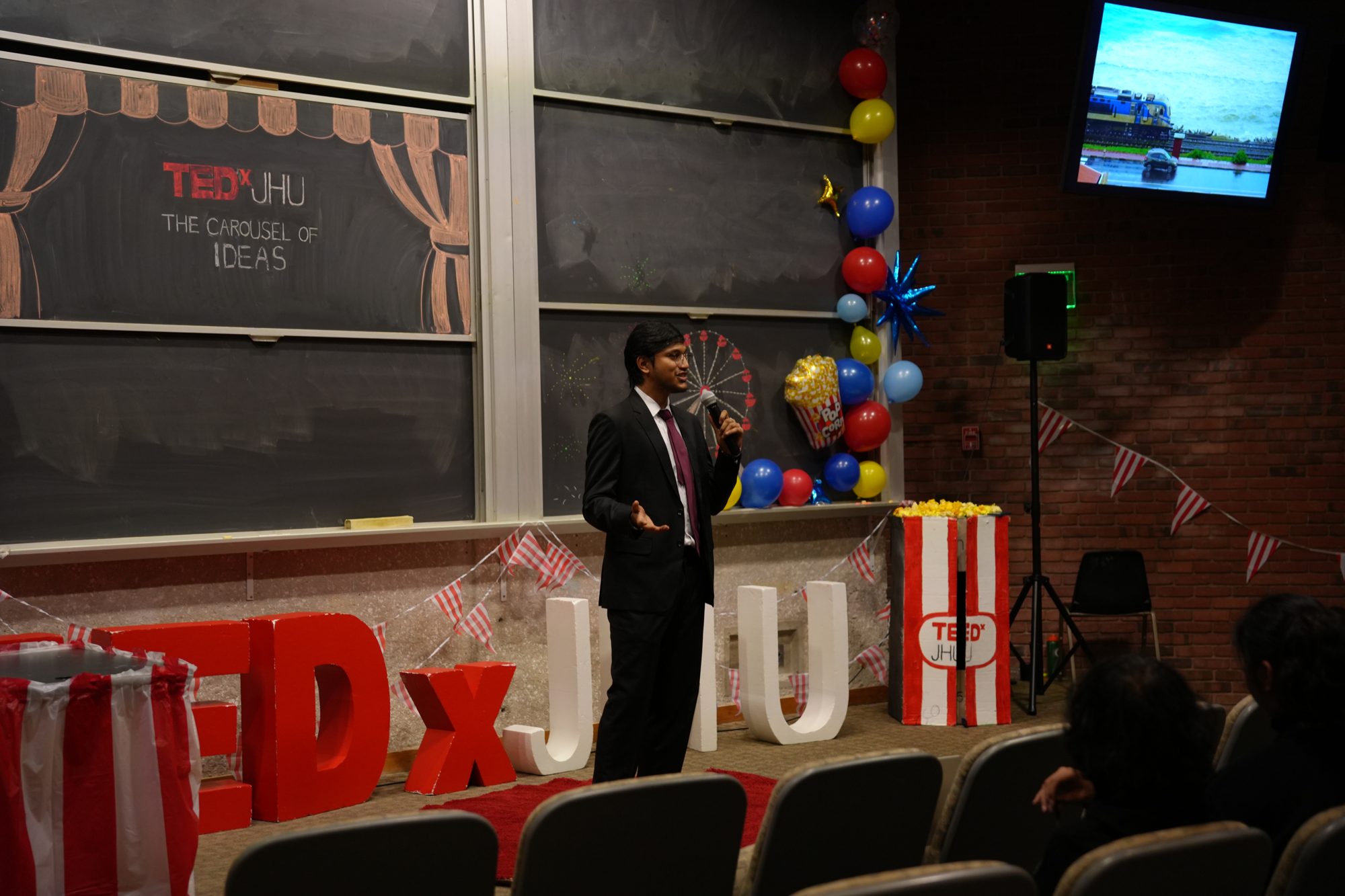 Devothama GN speaking on stage at TEDxJHU — The Carousel of Ideas, Johns Hopkins University 2025